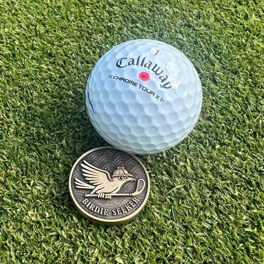 A Birdie Seeker marker resting on the green beside a golf ball