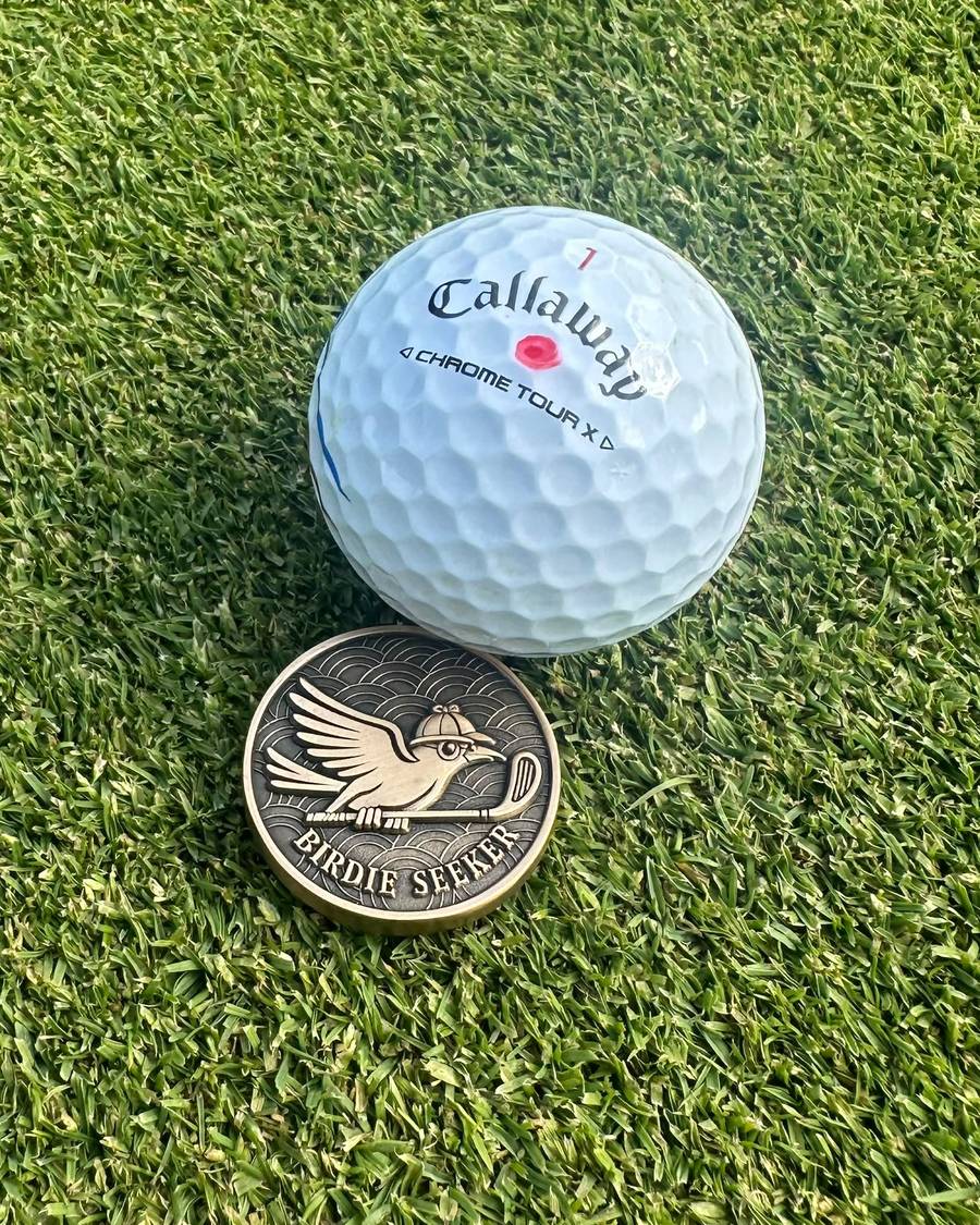 The Birdie Seeker marker sitting on the green next to a golf ball
